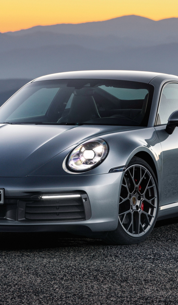 Серебристый автомобиль Porsche 911 Carrera 4S 2019 года на фоне гор 