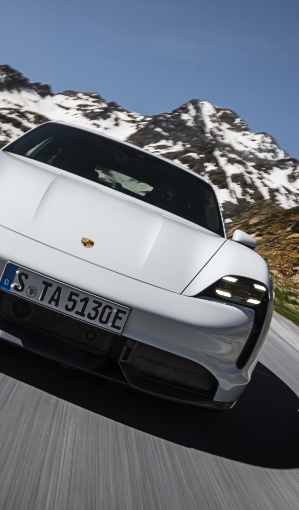 Белый автомобиль Porsche Taycan Turbo S 2019 года на фоне заснеженных гор