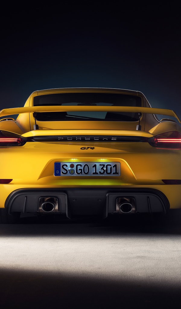 Желтый автомобиль Porsche 718 Cayman GT4, 2019 года вид сзади на сером фоне