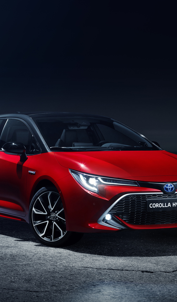 Красный автомобиль Toyota Corolla Hybrid 2018 года в свете фонарей
