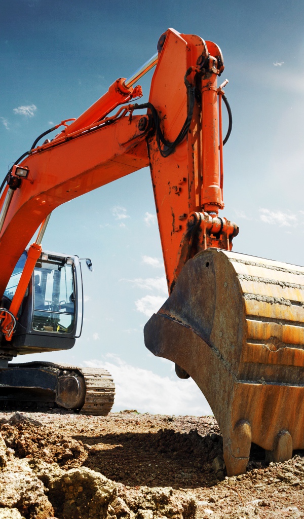 Экскаватор с ковшом на фоне голубого неба