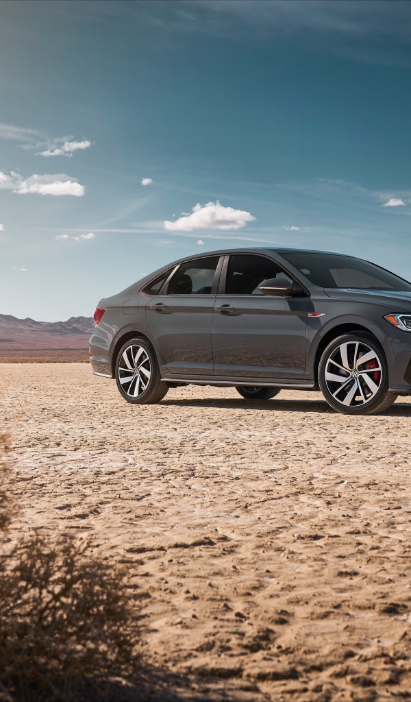 Стильный серебристый автомобиль Volkswagen Jetta на фоне неба 