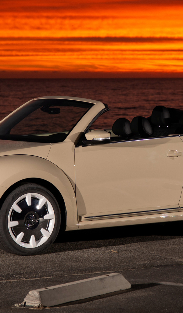 Белый кабриолет Volkswagen Beetle SEL на фоне океана на закате