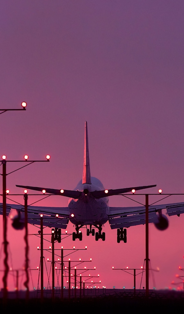 Пассажирский самолет идет на посадку на закате 