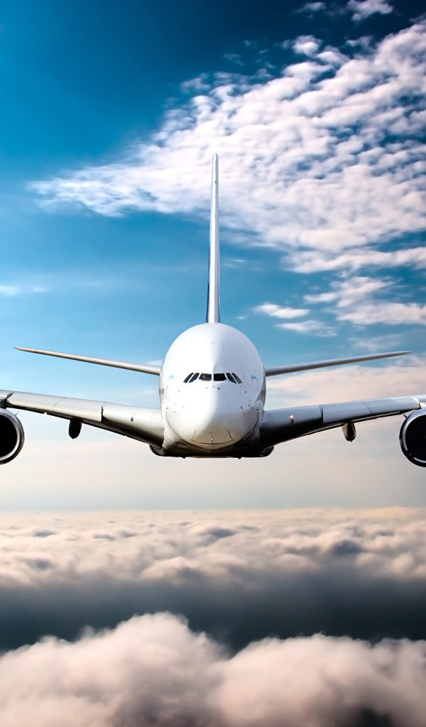 Самолет в белых облаках на фоне голубого неба