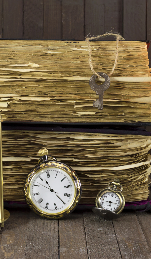 Старинные книги, зажженная свеча, ключи и часы на столе