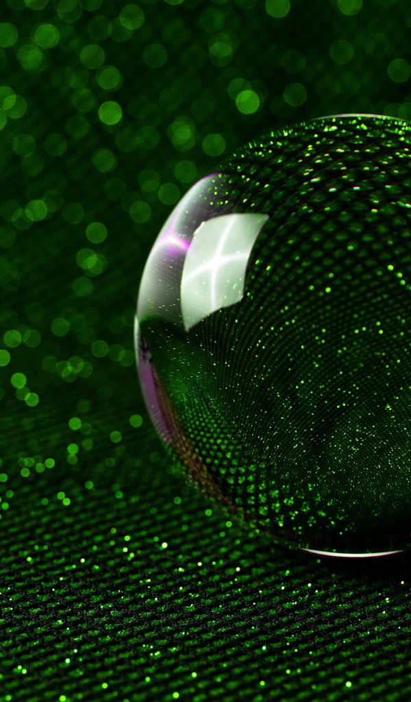 Большой стеклянный шар на зеленом блестящем фоне