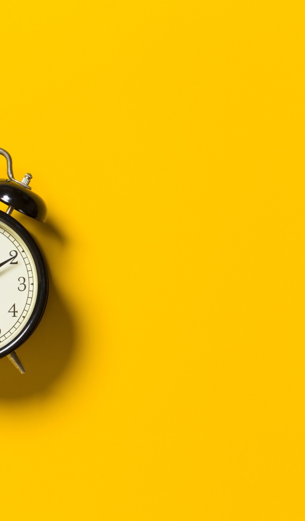 Черный будильник на желтом фоне