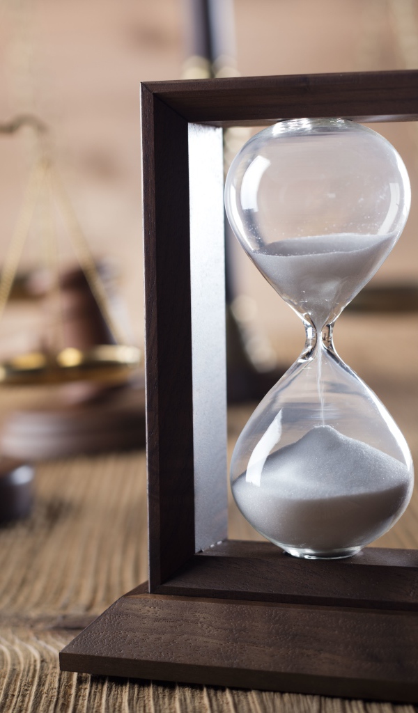 Песочные часы на столе с весами крупным планом