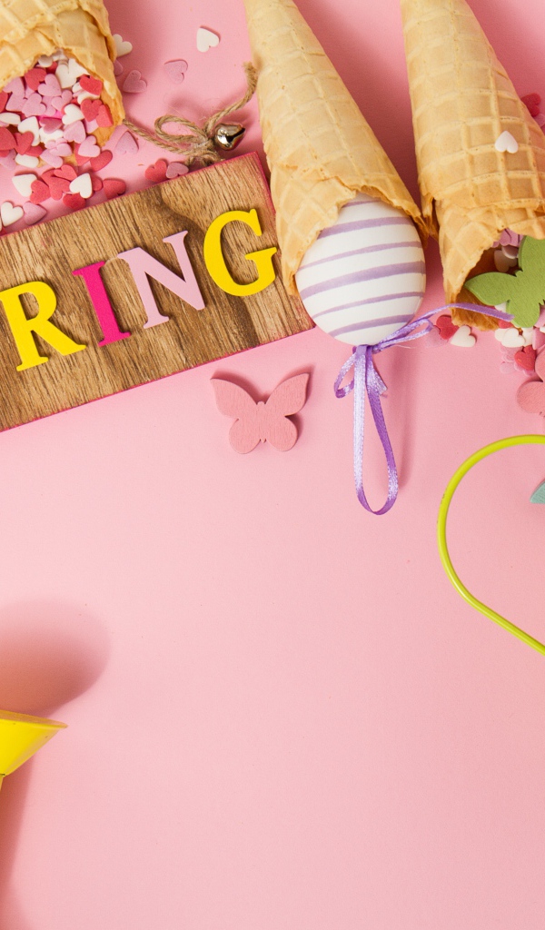 Надпись весна с вафельными рожками и яйцами на розовом фоне