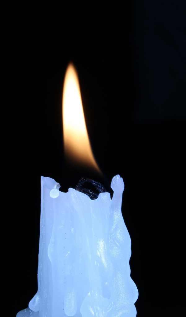 Зажженная свеча на черном фоне
