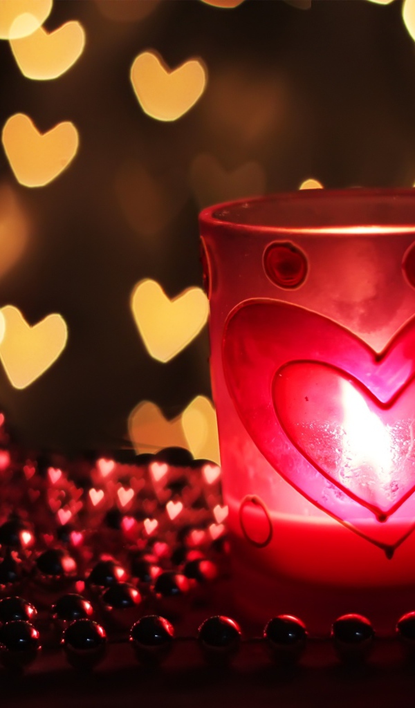 Зажженная свеча на столе с бусами 