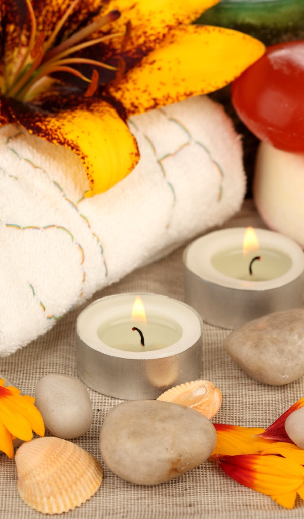 Зажженные свечи на столе с полотенцем, цветами и мылом