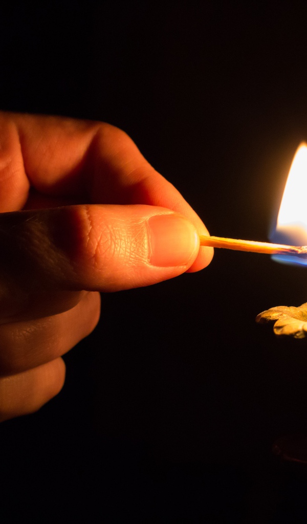 Рука со спичкой поджигает свечу