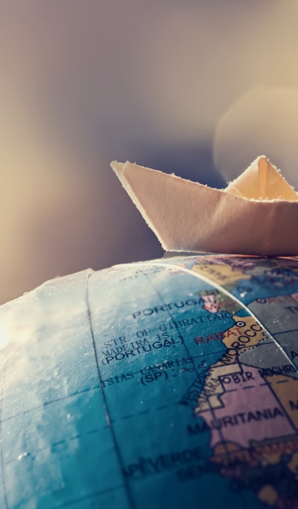 Бумажный кораблик лежит на глобусе