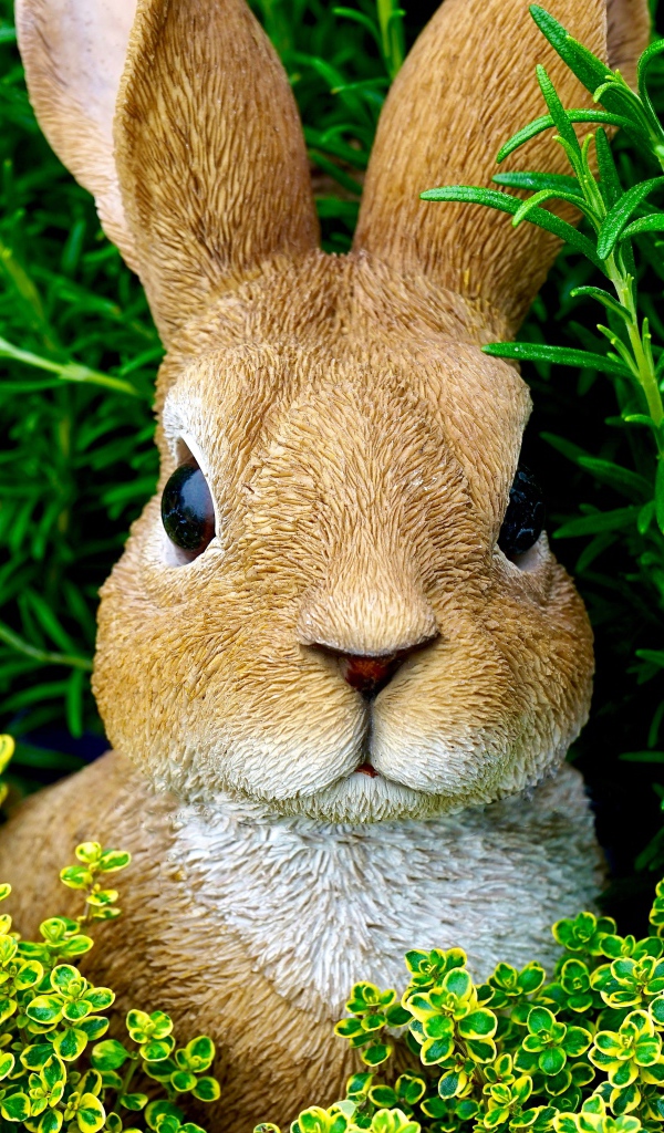 Статуэтка кролика в зеленой траве 