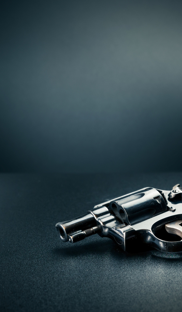 Револьвер с пулями на сером фоне