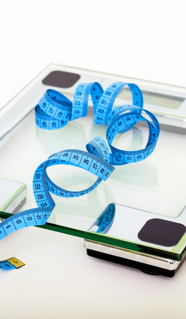 Весы на полу с сантиметром на белом фоне