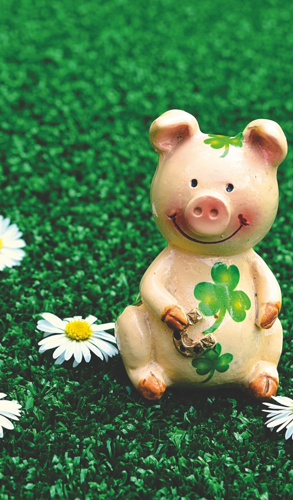 Статуэтка поросенка на зеленой траве с ромашками