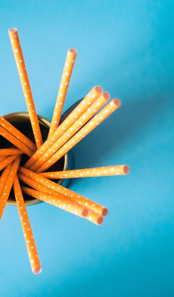 Трубочки в стакане на голубом столе