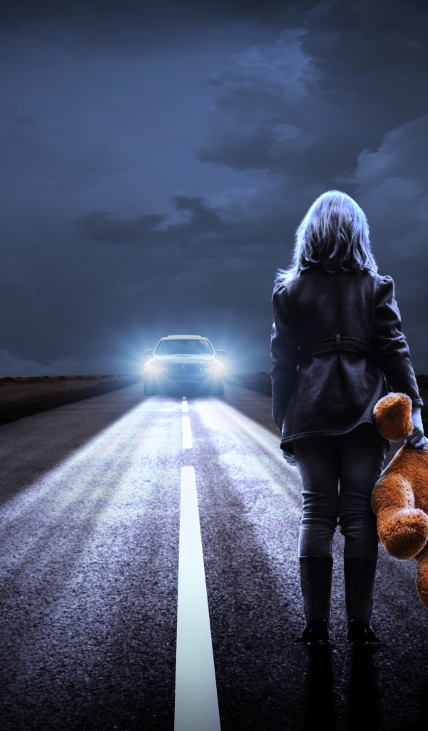 Девушка стоит на дороге с игрушечным медведем