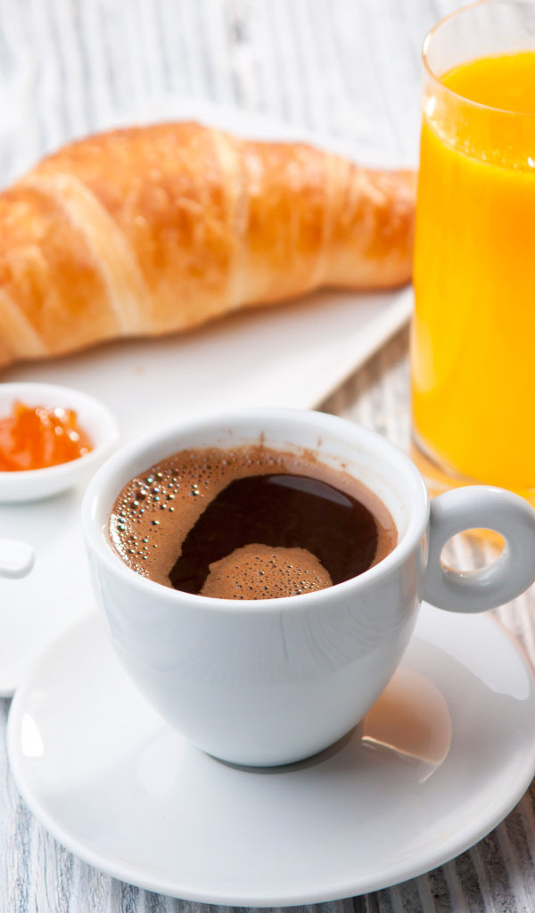 Чашка кофе на столе с соком и круассаном