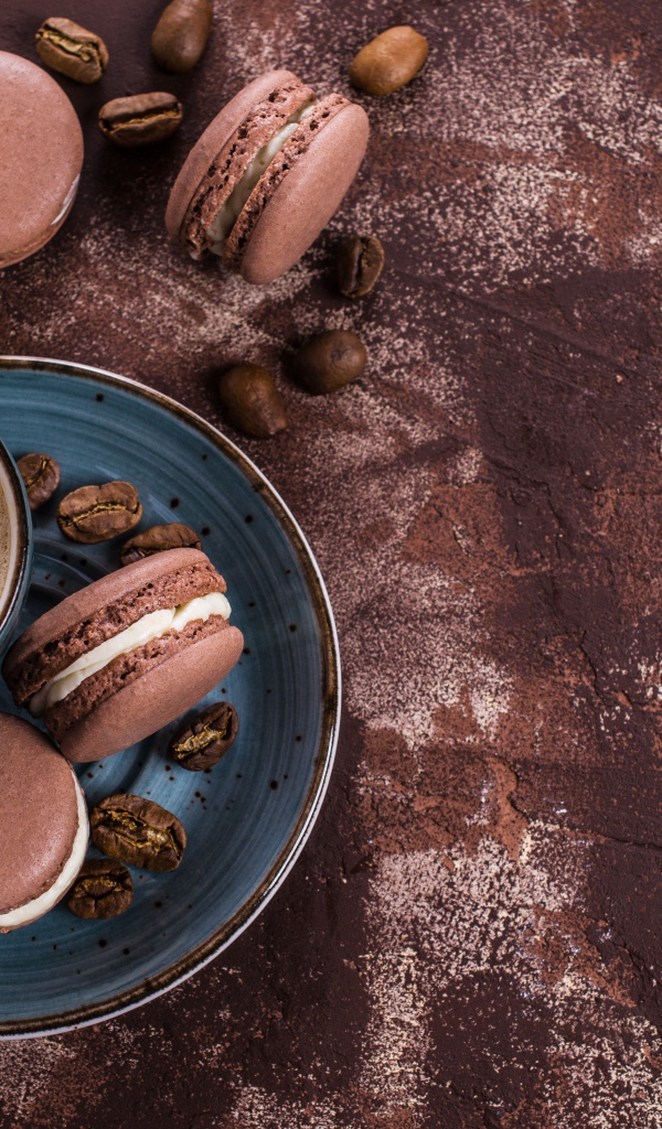 Чашка кофе с шоколадными макарунами на столе