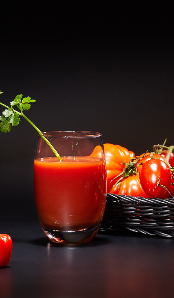 Стакан томатного сока на столе с помидорами
