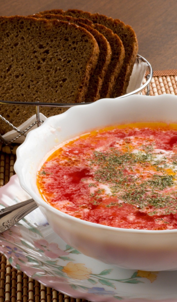 Тарелка красного борща на столе с сыром и черным хлебом