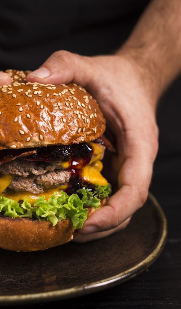 Большой сочный гамбургер в руках