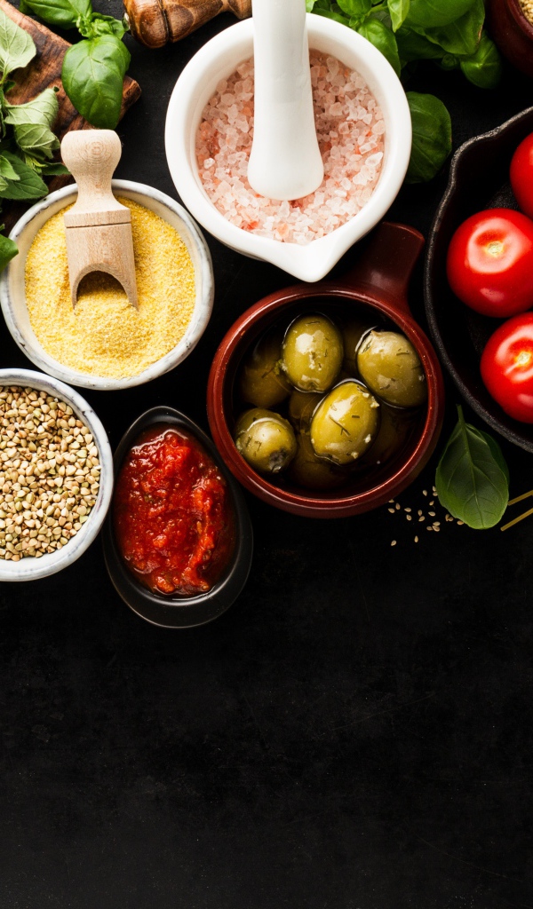 Крупы на столе с зеленью, помидорами, оливками и спагетти