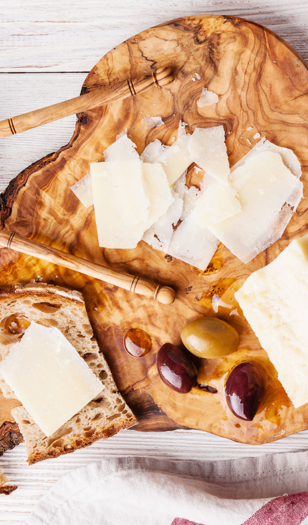 Сыр на доске с хлебом и и оливками