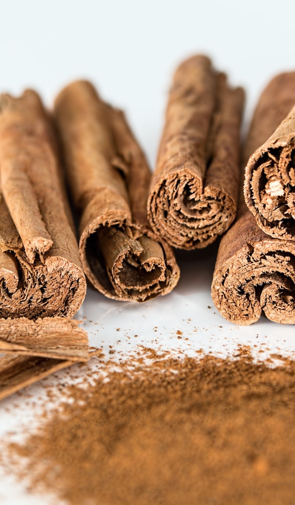 Палочки корицы на белом фоне с молотой