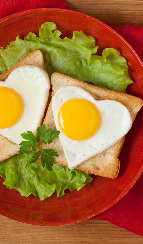 Гренки с яичницей на тарелке с листьями салата 