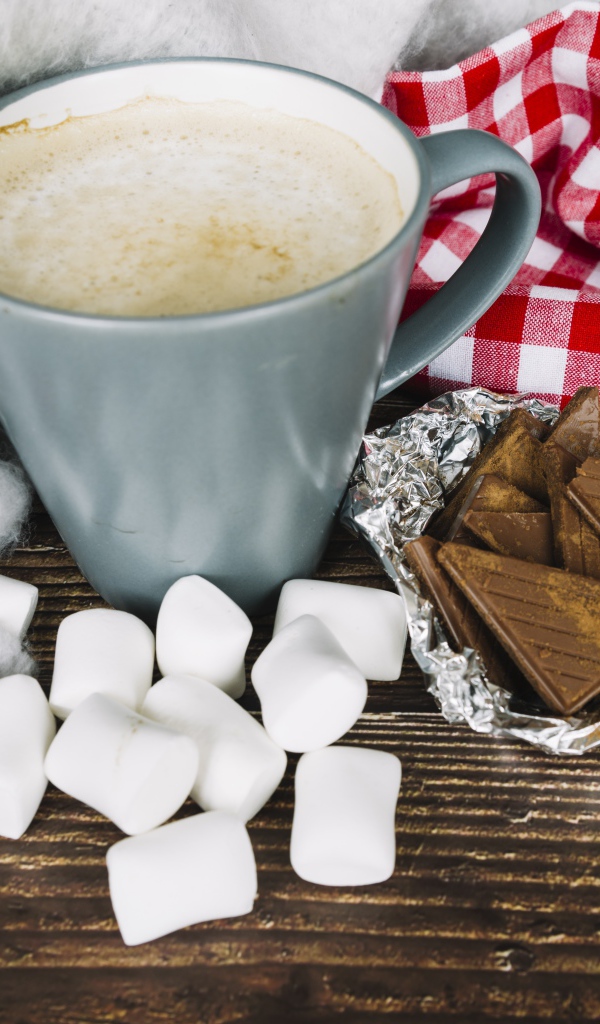 Чашка кофе на столе с маршмеллоу и шоколадом