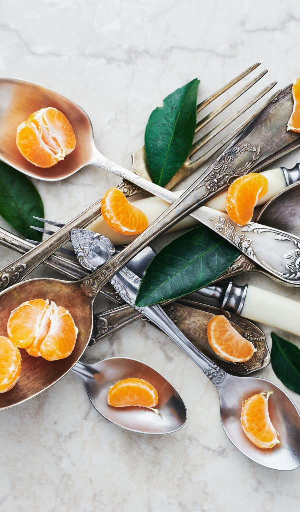 Столовые приборы на столе с дольками мандарина