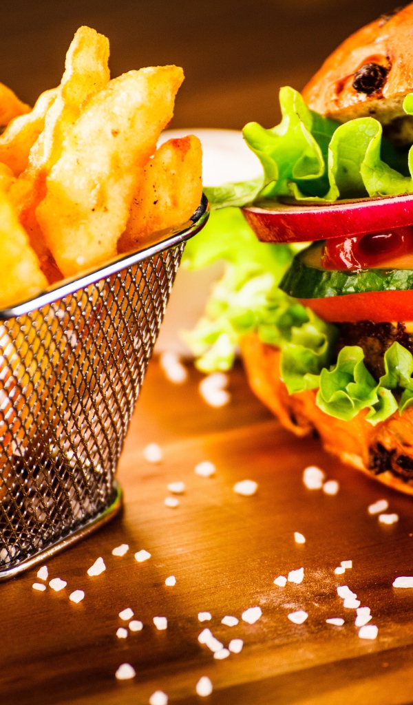 Аппетитный сочный гамбургер на доске с картошкой фри и соусом