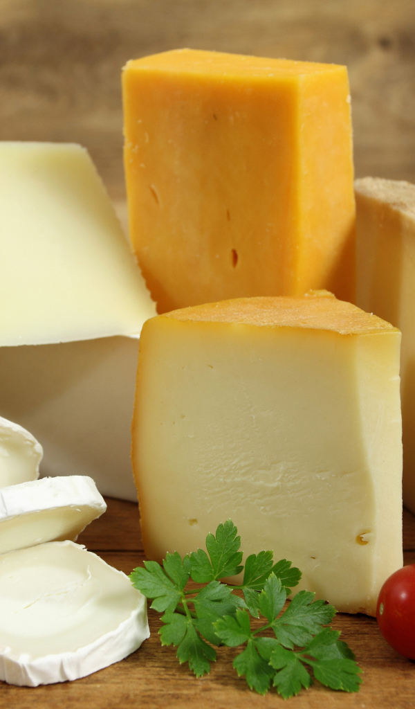 Разные виды твердого сыра на столе с помидорами и петрушкой