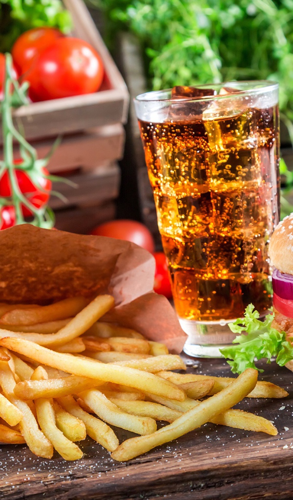 Картофель фри, гамбургер, кола и помидоры на столе