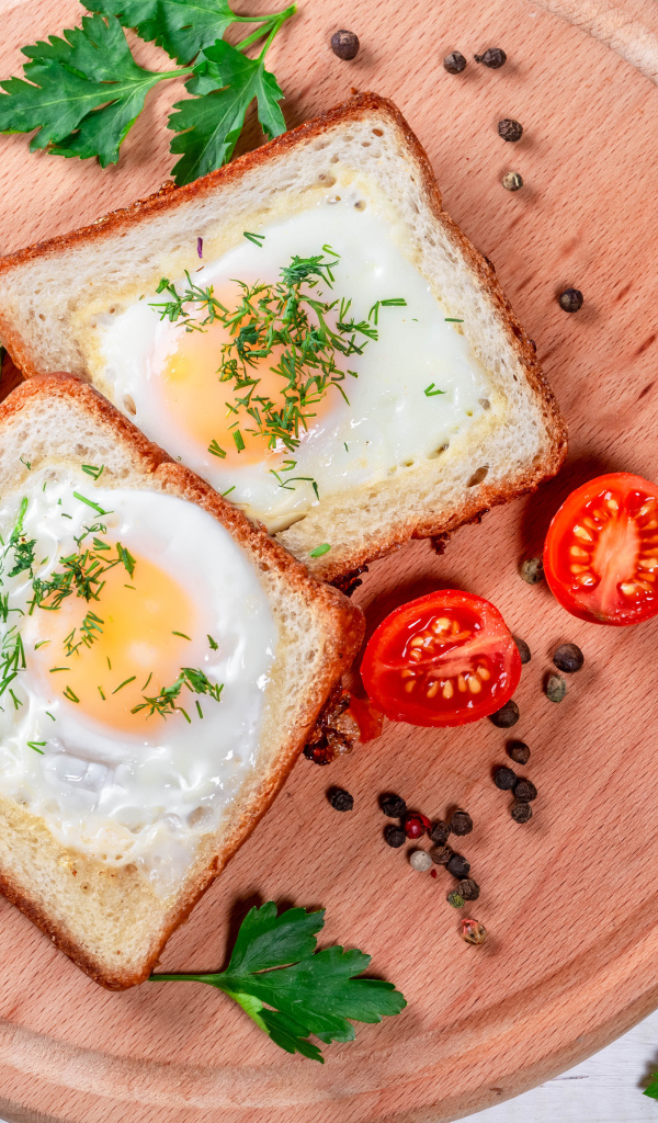 Яичница в хлебе на доске с помидорами, огурцами и петрушкой