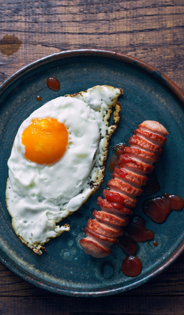 Яичница с сосиской на столе с морковью 