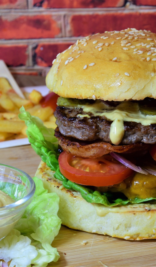 Гамбургер с беконом на столе с соусом и картофелем фри