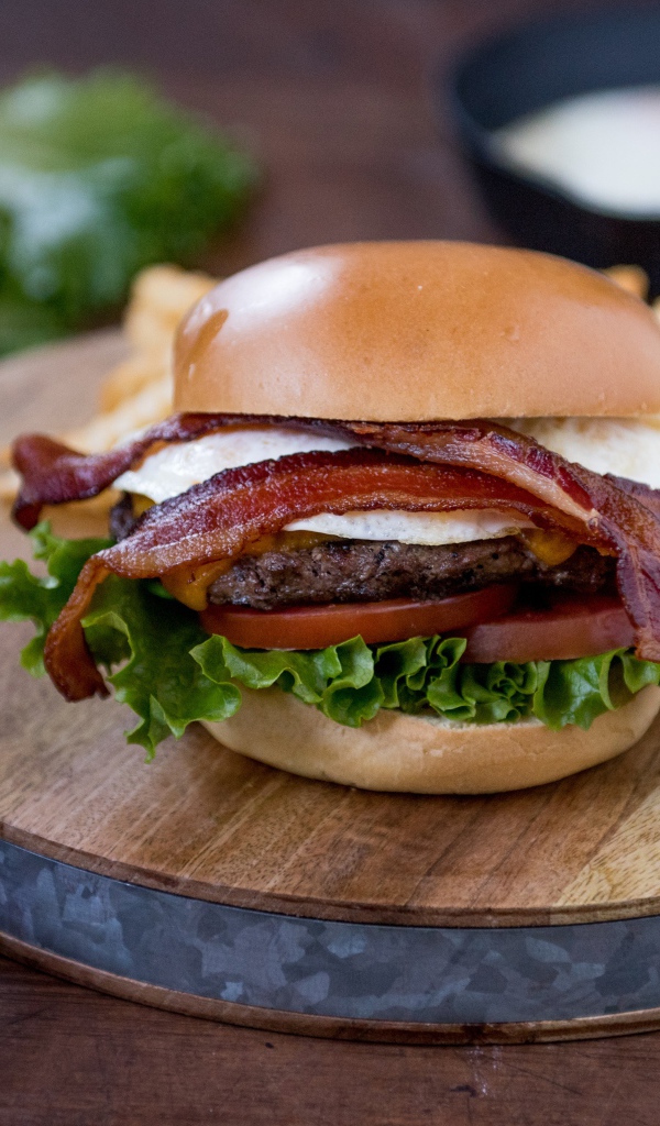 Гамбургер с беконом на столе с овощами