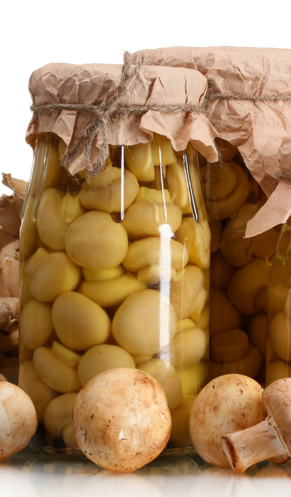 Маринованные шампиньоны в банках на белом фоне со свежими