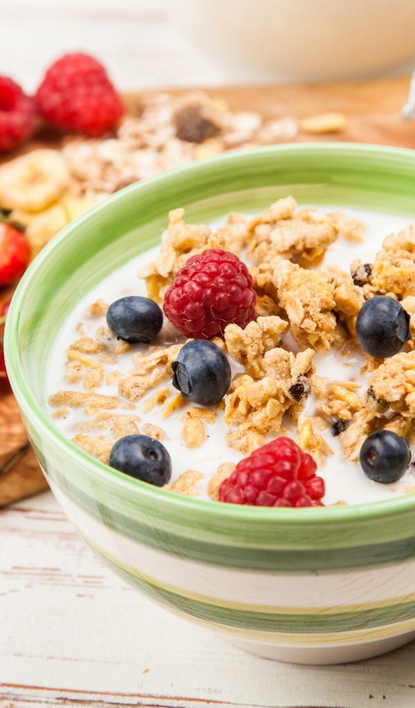 Мюсли с молоком и ягодами на столе к завтраку