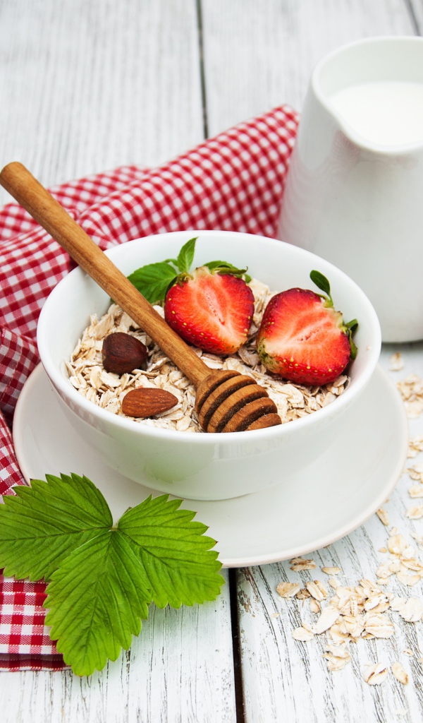 Овсяная каша на столе с молоком и клубникой