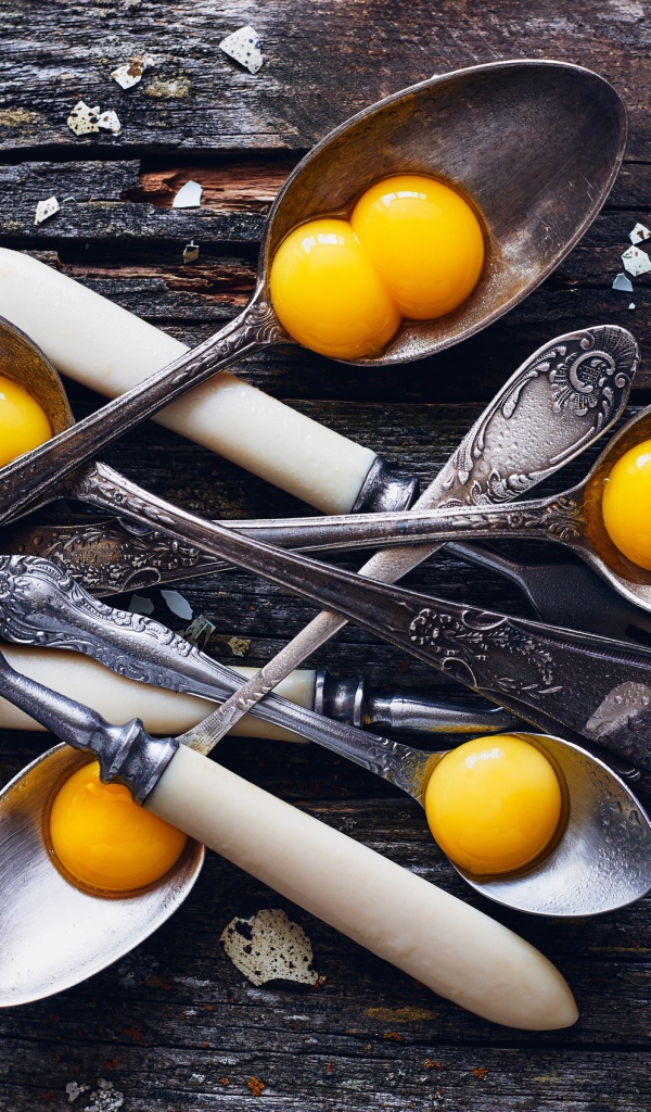 Старые ложки с желтками на деревянном столе