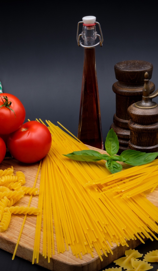 Макаронные изделия на столе с мукой, помидорами и специями