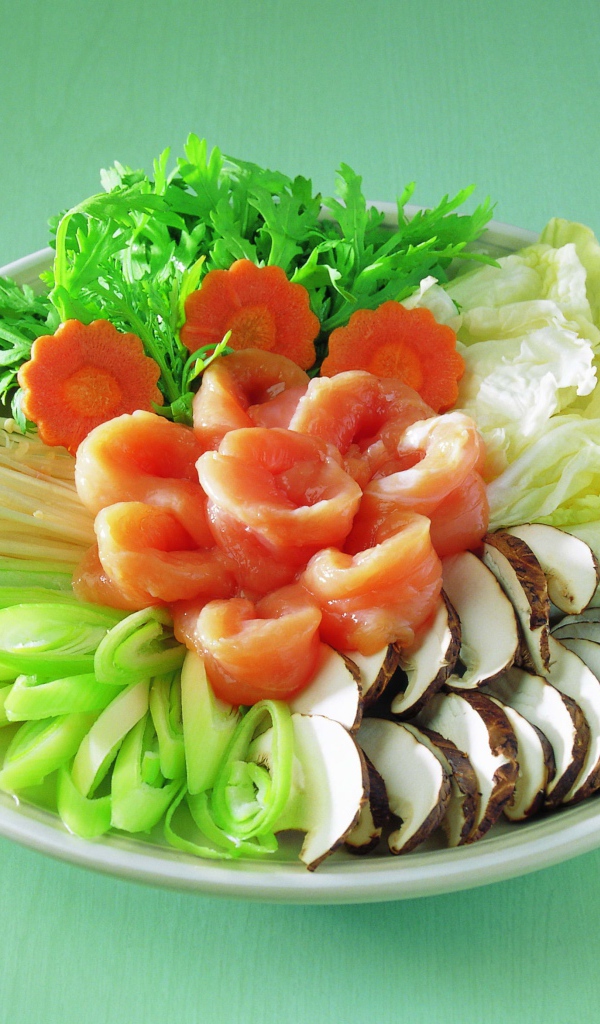 Тарелка с овощами и красной рыбой на зеленом фоне