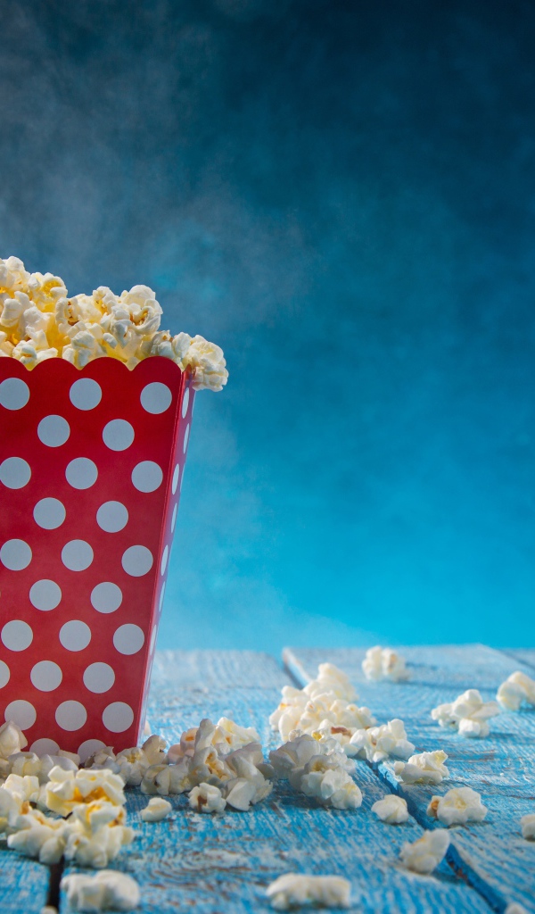 Попкорн в картонном пакете на голубом столе 